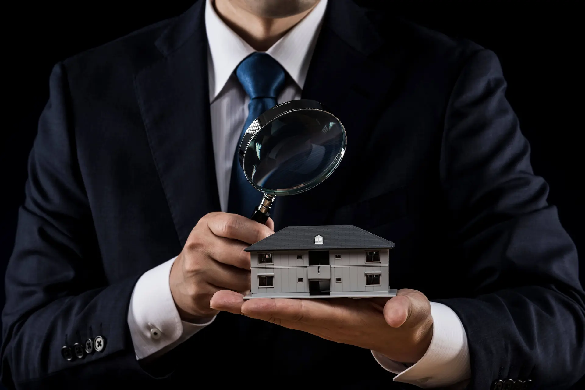 dpe vente - un agent immobilier tenant une maison miniature dans sa main et la passant à la loupe